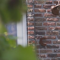 Detail van bakstenen muur met koperen lamp bij Vakantiehuis in Scheulder, Limburg.