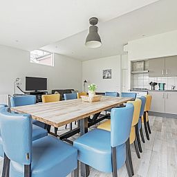 Ruime eetkamer in bungalow Anemoon 12, Walem, Zuid Limburg. Gezellige binnenruimte met moderne keuken en kleurrijke stoelen.