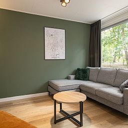 Gezellige woonkamer in Bungalow 4, vakantiehuis in Vlierden, De Peel, Noord Brabant met comfortabele zithoek en uitzicht op de natuur.