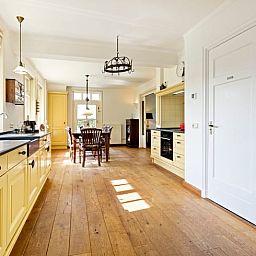 Ruime keuken in Vakantiehuisje in Deurne, Noord Brabant, met houten vloeren en veel lichtinval, ideaal voor een ontspannen verblijf.