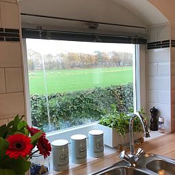 Keukenraam met uitzicht op groene velden bij Huisje in Baarle-Nassau, vakantiewoning in Kempen.