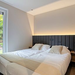 Sfeervolle slaapkamer in vakantiehuis Bosven, Oisterwijk, Hart van Brabant, met uitzicht op de groene natuur van Noord Brabant.