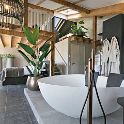 Geraeumiges Schlafzimmer im Ferienhaus in Moergestel, Nordbrabant, mit Holzbalken und bequemem Bett.