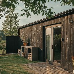 Sunny garden of Holiday Home in Chaam, North Brabant with modern wooden finishes and natural surroundings.