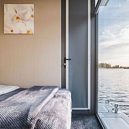 Schlafzimmer mit Blick auf das Wasser im Ferienhaus in Woudrichem, Nordbrabant.
