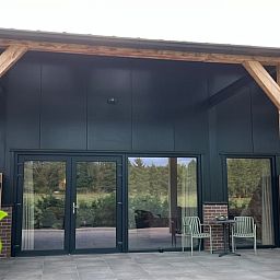 Moderne Veranda im Huisje in De Moer, Ferienhaus in Nordbrabant mit Blick auf die gruene Umgebung.