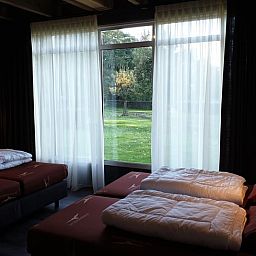 Ruime slaapkamer met grote ramen in Vakantiehuis in Schaijk, omgeven door groene natuur in Noordoost Brabant.