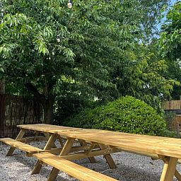 Ruime picknicktafel onder bomen bij Vakantiehuis in Overloon, perfect voor buitenmaaltijden in Noord Brabant.