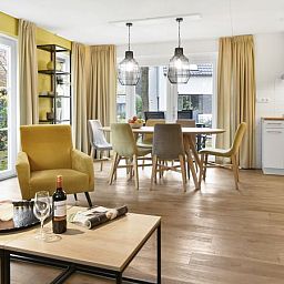 Moderne woonkamer in De Vers 6-persoons bungalow 6C2, Overloon, met open keuken en houten vloer.