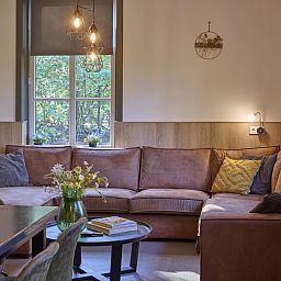 Gezellige woonkamer van vakantiehuis Bosbeertje 43 45 in Erp, Noordoost Brabant, met comfortabele bank en sfeervolle verlichting.