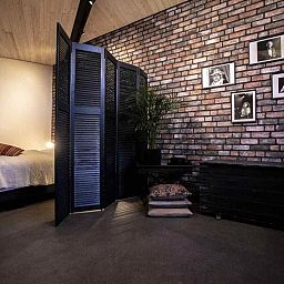 Attractive bedroom in BRA045 vacation home Geffen with brick wall and artwork.