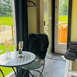 Gezellige binnenruimte van Huisje in Ledeacker, vakantiehuis in Noordoost Brabant, met uitzicht op groene velden en een knus tafeltje.