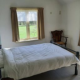 Sfeervolle slaapkamer in Vakantiehuisje in Keent, Noordoost Brabant, met uitzicht op groene velden en rustieke inrichting.