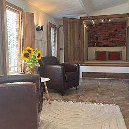 Geraeumige Sitzecke im Cottage in Hoogerheide, Ferienhaus in Hoogerheide, mit Ledersesseln und einem Fernseher.