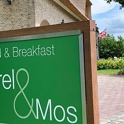 Ontdek de charmante Bed & Breakfast Merel & Mos in Moerstraten, West Brabant, met een uitnodigend bord en groene omgeving.