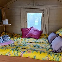Comfortabele slaapkamer in Wagen Cosy, Spaarndam, met kleurrijk beddengoed en knusse sfeer, ideaal voor een bijzondere overnachting in Noord-Holland.