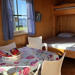 Gemuetlicher Innenraum eines Ferienhauses in Julianadorp an der Nordseekueste, Nordholland, mit Essbereich und Etagenbett.