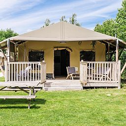 Strandtent 8 personen in Julianadorp, Noord-Holland, biedt een glamping ervaring met een ruime veranda en uitzicht op de groene omgeving.