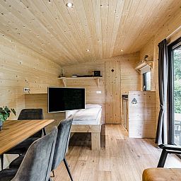 Gemuetliches Zimmer in der Woodlodge fuer 4 Personen in Julianadorp, Nordseekueste, Nordholland mit Holzausstattung und Blick auf die Terrasse.