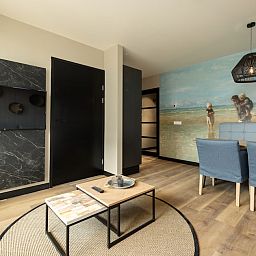 Stijlvolle woonkamer van Appartement 3A in Egmond aan Zee, Noordzeekust, Noord-Holland met modern interieur en kunstzinnige muurdecoratie.