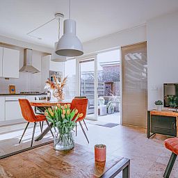 Modernes Wohnzimmer des Ferienhauses Zeebaars in Egmond aan Zee mit offener Kueche und Gartenblick, Nordseekueste, Nordholland.