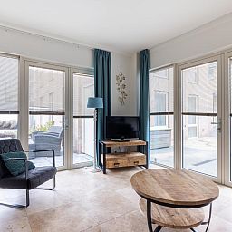 Bright living room in holiday home De Platvis, Egmond aan Zee, with large windows and modern furnishings on the North Sea coast in North Holland.