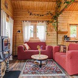 Gemuetliches Wohnzimmer des Ferienhauses in Callantsoog, Nordseekueste, Nordholland mit Holzofen und bunter Dekoration.