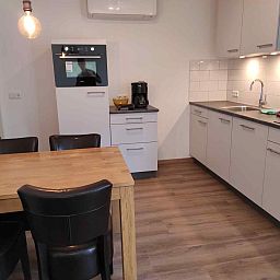 Gemuetliches Wohnzimmer des NH213 Ferienhauses in Callantsoog, Nordholland, mit bequemen Sofas und Essecke.