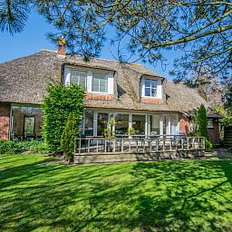 Landhuis Duinzicht in Callantsoog, een charmant vakantiehuis aan de Noordzeekust met rieten dak en zonnig terras te midden van groene natuur.