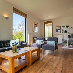 Gezellige woonkamer van Landhuis Duinzicht in Callantsoog, Noordzeekust, Noord-Holland, met uitzicht op de natuur en comfortabele zithoek.