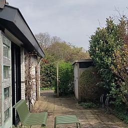 Entspannte Terrasse am Haus in Egmond-Binnen, Ferienhaus an der Nordseekueste, Nordholland, umgeben von gruener Natur.