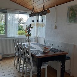 Eetkamer in vakantiehuis Rekere 111, Schoorldam, Noordzeekust, Noord-Holland met houten tafel en sfeervolle verlichting.