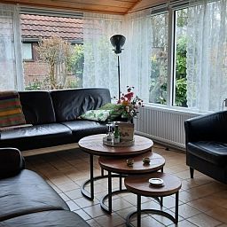 Lichte zithoek in vakantiehuis Rekere 111, Schoorldam, Noordzeekust, Noord-Holland met grote ramen en comfortabele stoelen.