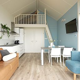 Moderne binnenruimte van Beach House Comfort 4 in Julianadorp aan Zee, Noord-Holland, met comfortabele zithoek en eetruimte.