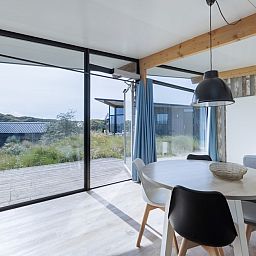 Helles Interieur des Sea House Special Ferienhauses in Overveen, Nordseekueste, mit Blick auf Terrasse und Duenen.