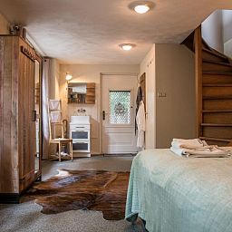 Stijlvolle slaapkamer in Casa Allegria, Bergen, met houten trap en rustieke inrichting voor een ontspannen verblijf.