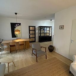 Geraeumiges Wohnzimmer des Ferienhauses in Andijk, IJsselmeerkueste, Nordholland mit bequemer Sitz- und Essecke.