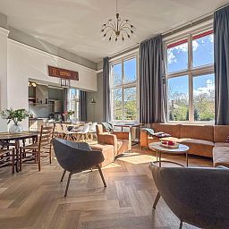 Lichte woonkamer van Groot Weeshuis vakantiehuis in Enkhuizen, Noord-Holland met ruime zithoek en grote ramen met uitzicht op de natuur.