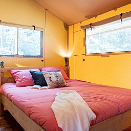 Cozy bedroom in De Bos Tent, an attractive glamping lodge in Huizen, North Holland, with cozy furnishings and natural light.