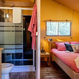 Cozy bedroom and modern bathroom in De Bos Tent, a glamping lodge in Huizen, IJsselmeer coast, North Holland.