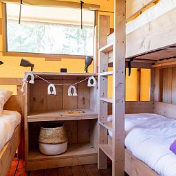 Cozy bedroom in De Bos Tent, a safari tent in Huizen, IJsselmeer coast, North Holland, with bunk beds and warm decor.