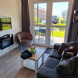 Gezellige woonkamer in Vrijstaande woning in Bovenkarspel, vakantiehuis aan de IJsselmeerkust, Noord-Holland met uitzicht op terras en tuin.