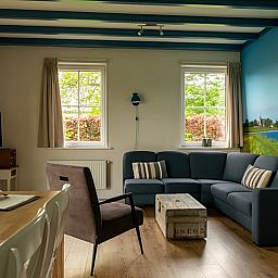 Erleben Sie Komfort im gemuetlichen Wohnzimmer des Ferienhauses in Schellinkhout, mit Blick auf die natuerliche Umgebung der IJsselmeerkueste.
