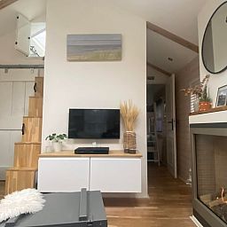 Cozy living room in Cottage in Schoorl, vacation home in North Holland with modern furnishings and a charming fireplace.