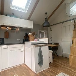 Cozy kitchen of Huisje in Schoorl, vacation home in North Holland, with modern furnishings and wooden details for a cozy atmosphere.