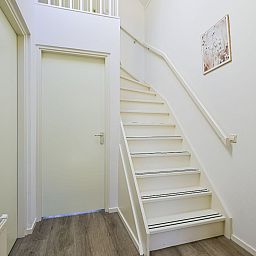Heldere hal met trap in de Vrijstaande woning in Schoorl, Noord-Holland noord, ideaal vakantiehuis voor gezinnen.
