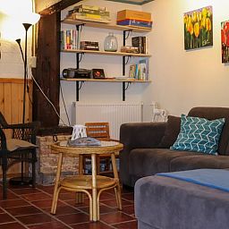 Cozy living room in Holiday home in Schoorl, North Holland with comfortable seating area and bookshelves for a relaxing stay.