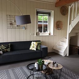 Gemuetliches Wohnzimmer im Huisje in Winkel, einem Ferienhaus in Nordholland Nord. Gemuetliche Sitzecke mit modernen Moebeln und natuerlichem Licht.