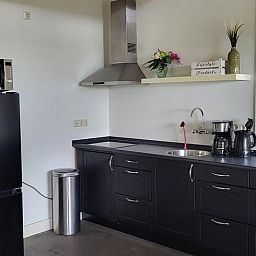Moderne Kueche im Ferienhaus Cottage in Winkel, Nordholland Nord, mit stilvollen schwarzen Schraenken und Geraeten fuer einen komfortablen Aufenthalt.