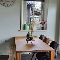 Gemuetliche Essecke im Ferienhaus in Winkel, Nordholland Nord, Ferienhaus mit Holztisch und Blumen am Fenster.